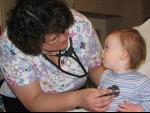 Nurse using a stethoscope on a young child